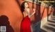 a woman in a red dress leaning against a wall