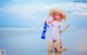 A woman with pink hair and a straw hat on the beach.