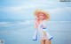 A woman in a straw hat standing on the beach.