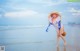 A woman in a straw hat is walking on the beach.