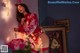 A woman in a red sweater and stockings holding a bouquet of flowers.