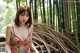 A woman in a floral dress posing in front of a bamboo fence.