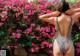 A woman in a leopard print swimsuit standing in front of pink flowers.