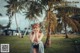 A woman standing in a grassy field next to palm trees.