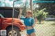 A woman in a blue bikini standing next to a red truck.