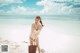 A woman standing on a beach holding a basket.