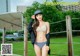 A woman in a bikini and a baseball cap posing for a picture.
