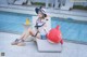 A woman sitting on a lounge chair next to a swimming pool.