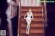 A woman in a white bodysuit sitting on a wooden staircase.