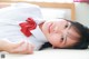 A woman in a white shirt and red bow tie laying on a bed.