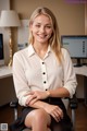 A woman sitting in an office chair smiling at the camera.